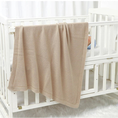 Couverture bébé tricot beige déposée sur lit bébé