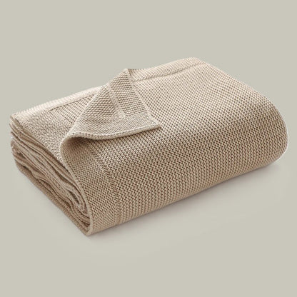 Couverture en tricot beige parfaitement pliée.