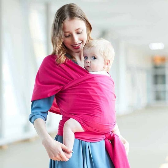 Bébé confortable contre maman dans écharpe de portage rose