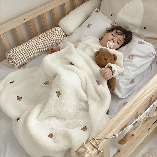 Enfant endormi avec sa couverture polaire et son ourson.