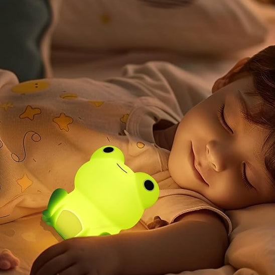 Enfant endormi avec sa veilleuse bébé grenouille dans ses bras.