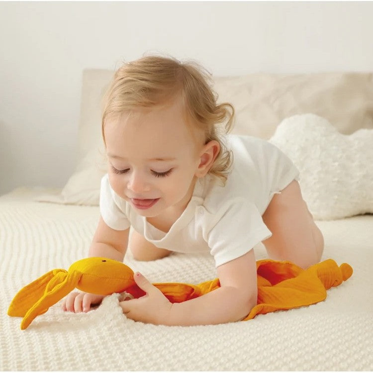 Enfant jouant sur lit avec doudou lapin