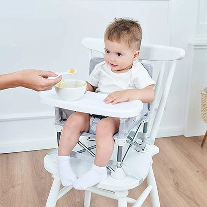 Enfant mangeant son repas dans sa chaise haute bébé compacte.