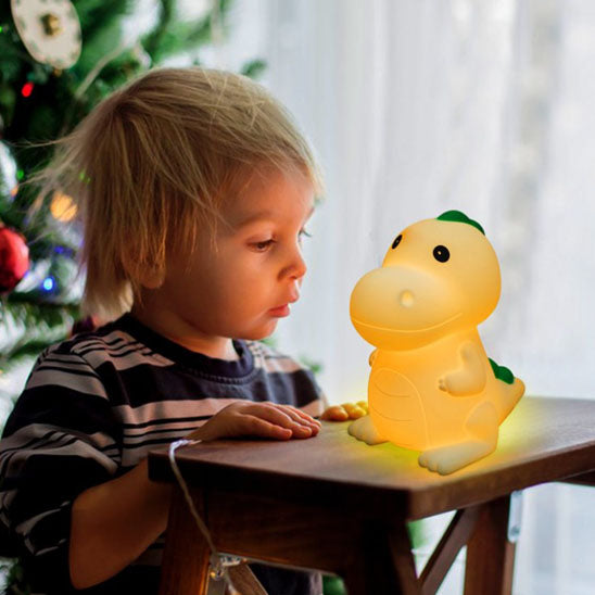 Enfant regardant veilleuse bebe dino déposée sur table