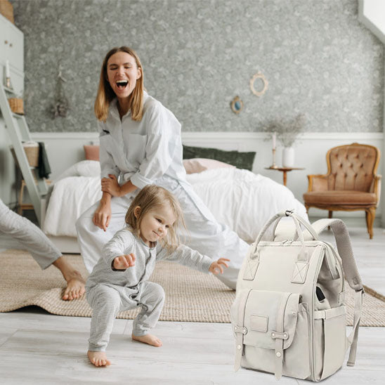 Famille rigolant dans chambre et sac à dos à langer vanille