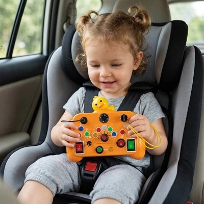 Fillette en voiture jouant avec son Busy board bebe orange.