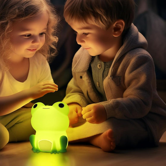 Fillette et garçonnet jouant avec leur veilleuse bébé grenouille.