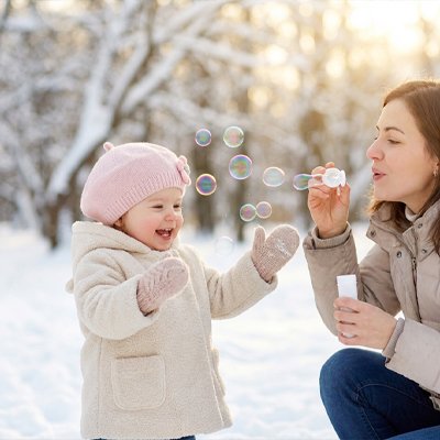 Fillette jouant dehors en hiver et qui porte son bonnet bebe rose.