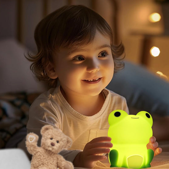 Fillette touchant sa veilleuse bébé grenouille lumineuse.