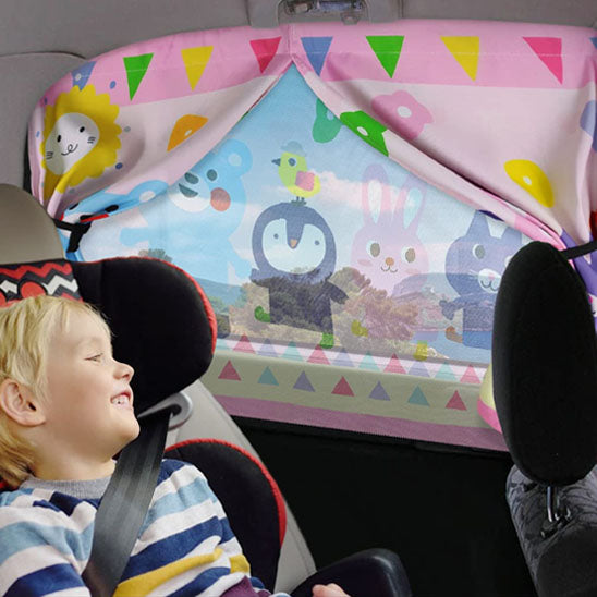 Garçon en voiture protégé par son pare soleil voiture bébé rose.