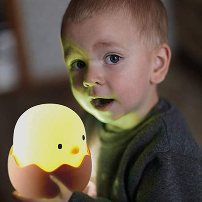 Garçon tenant sa veilleuse bébé poussin lumineux