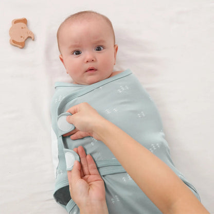 Mains qui enveloppent bébé dans couverture emmaillotage