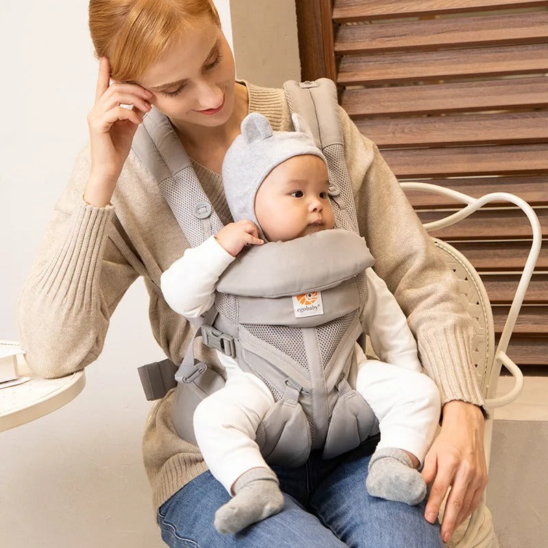 Maman assise regarde bébé dans porte bébé confortable