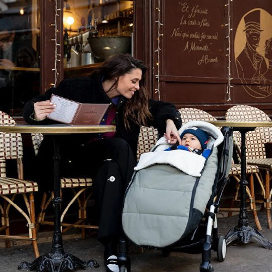 Maman dans un café surveillant bébé dans chancelière poussette