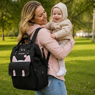 Maman en promenade avec bébé et son sac a dos a langer chat noir.