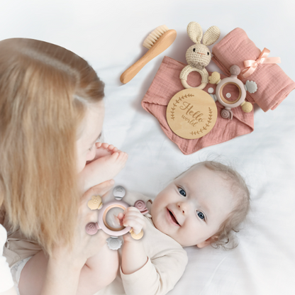 Maman joue avec son enfant et son hochet bébé et un ensemble cadeau rose.