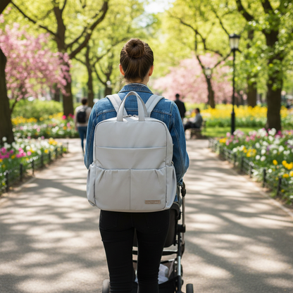 Maman avec son sac a dos a langer gris au parc au printemps.