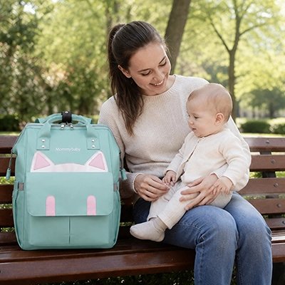Maman sur un banc de parc avec son sac a dos a langer chat vert.