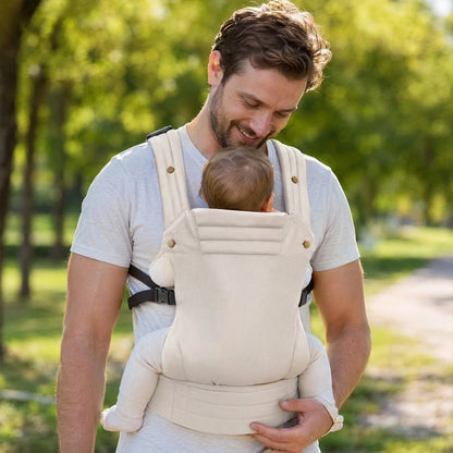 Papa en promenade avec son porte bebe ergonomique beige.
