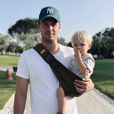 Papa promenant son enfant dans une echarpe de portage noire.