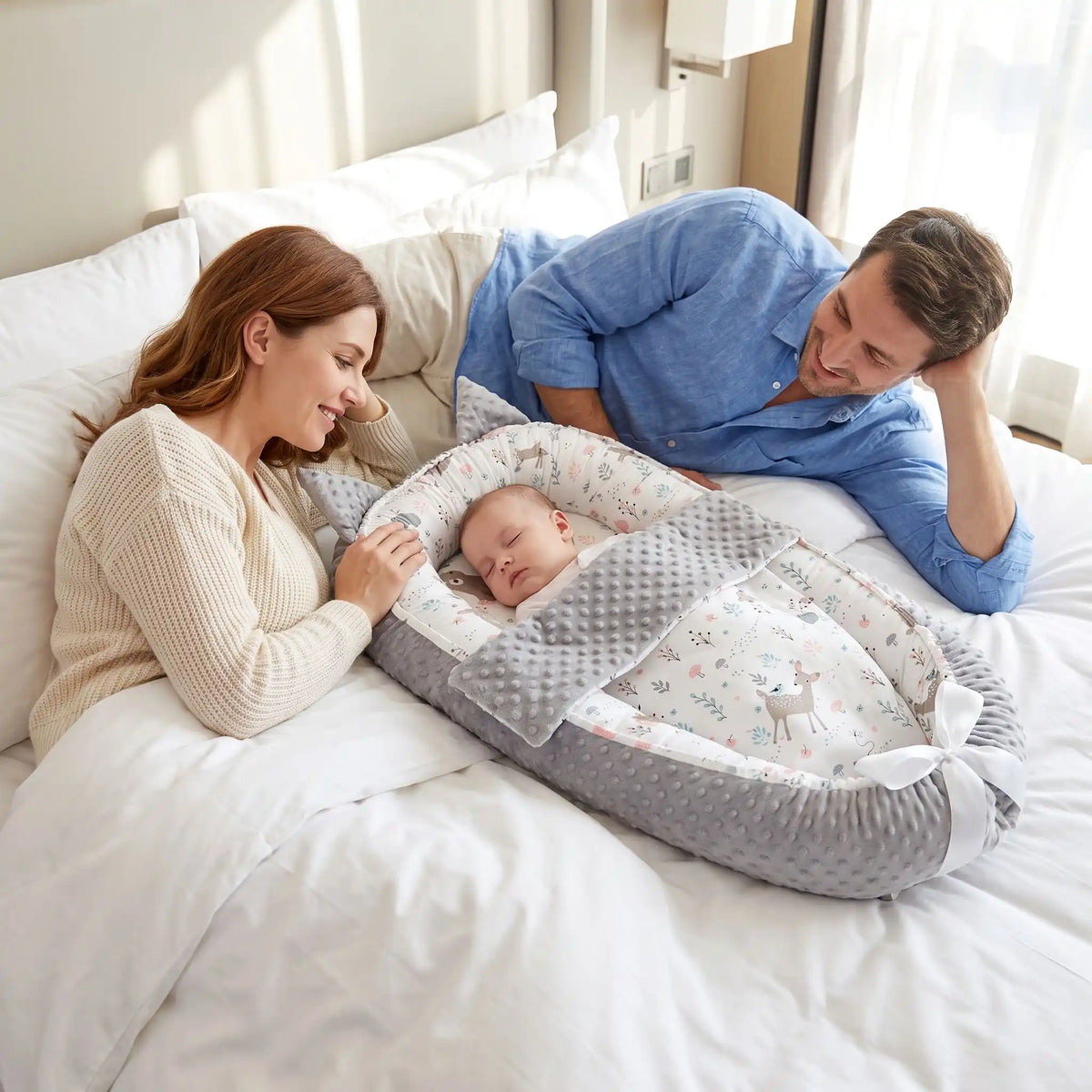 Parents regardant leur bébé endormi dans son nid d'ange sur un lit d'hôtel.