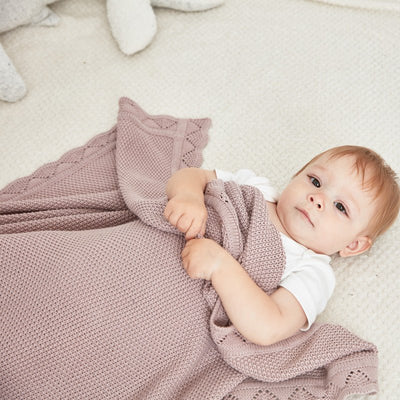 Petit bébé couché avec sa couverture bebe en tricot.