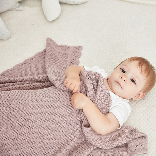 Petit bébé couché avec sa couverture bebe en tricot.