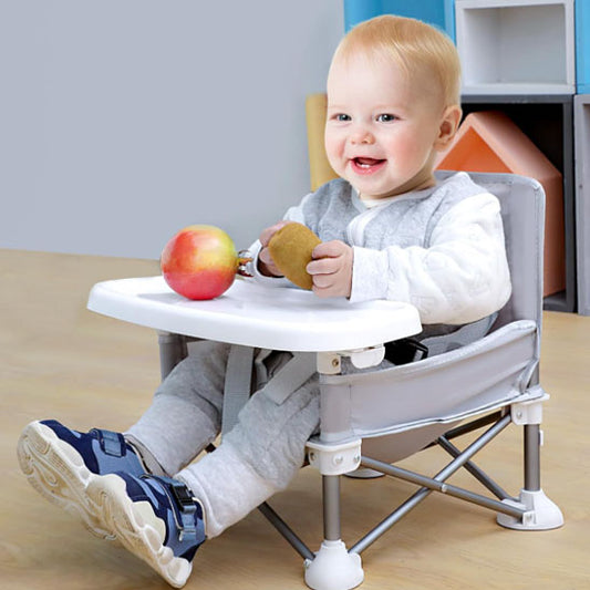 Petit garçon assis dans une chaise haute bebe portable