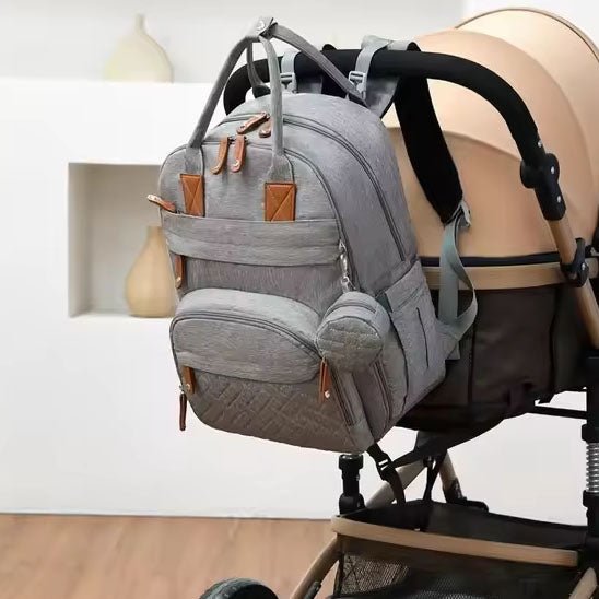 Sac à dos à langer accroché sur la poignée de la poussette bébé.