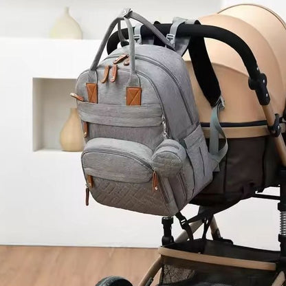 Sac à dos à langer accroché sur la poignée de la poussette bébé.
