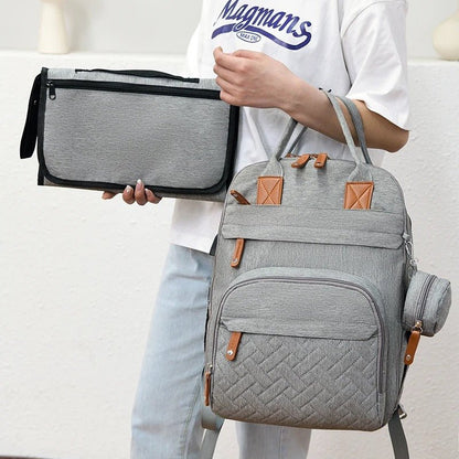 Femme tenant un sac à dos à langer avec un matelas à langer.