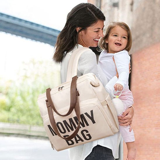 Maman et fillette souriantes avec sac a langer haut de gamme.