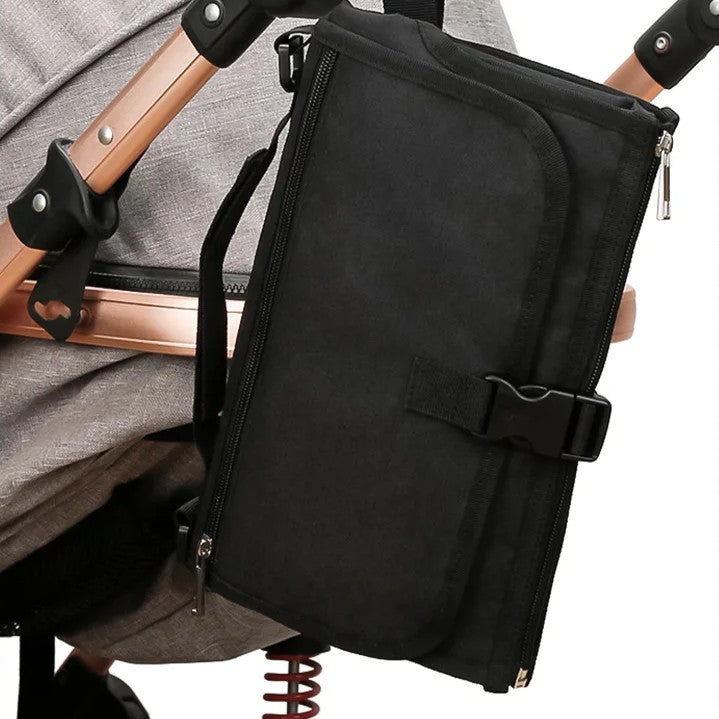 Tapis à langer nomade noir accroché à la poussette.