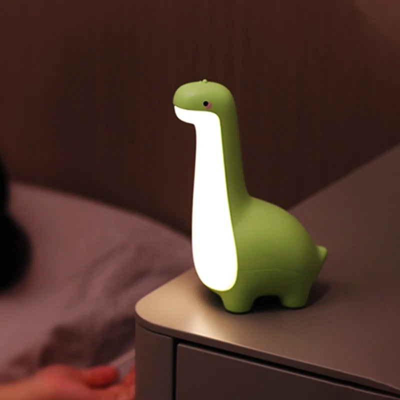 Veilleuse dinosaure verte sur table de chevet